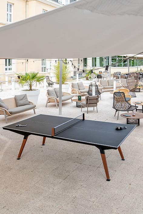 Table de ping pong extérieur avec deux raquettes sur une terrasse d'un hotel